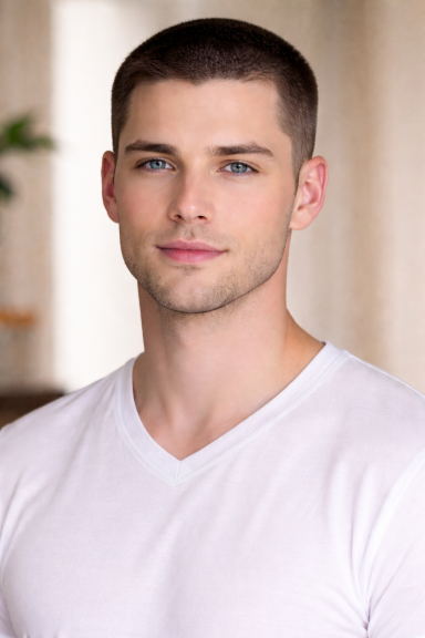 Junger Mann mit sehr kurzem Haar, trägt ein weißes T-Shirt, freundlicher Gesichtsausdruck.